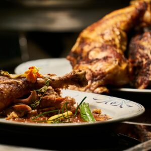 Close-up of a deliciously roasted chicken dish served with garnish, highlighting fine cuisine.