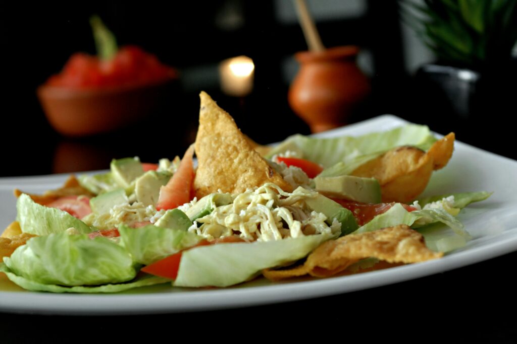 Delicious Mexican salad featuring avocado, lettuce, tomato, and crispy chips on a plate.