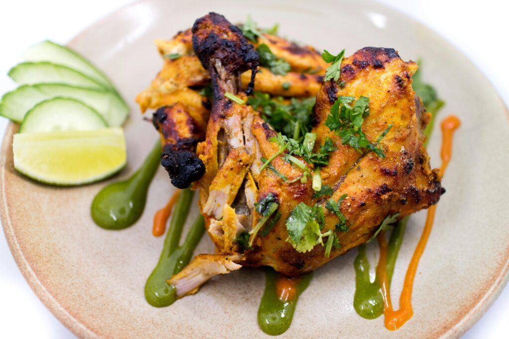 Delicious spicy grilled chicken garnished with cilantro and lime, perfect for a tasty meal.