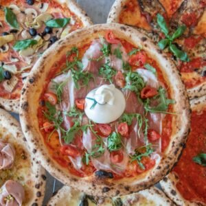Top view of assorted gourmet pizzas with fresh toppings such as ham, cheese, and vegetables, perfect for food photography.