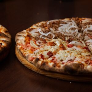Close-up of two delicious pizzas with pepperoni and onions on a wooden table.