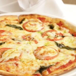 Delicious Margherita pizza topped with fresh tomatoes, mozzarella, and basil on a white plate.