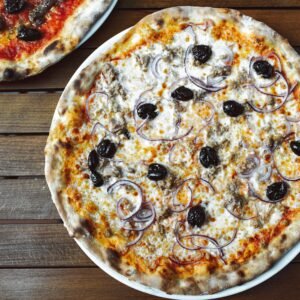 Mouth-watering Italian pizza topped with mozzarella, olives, and onions on a wooden table.